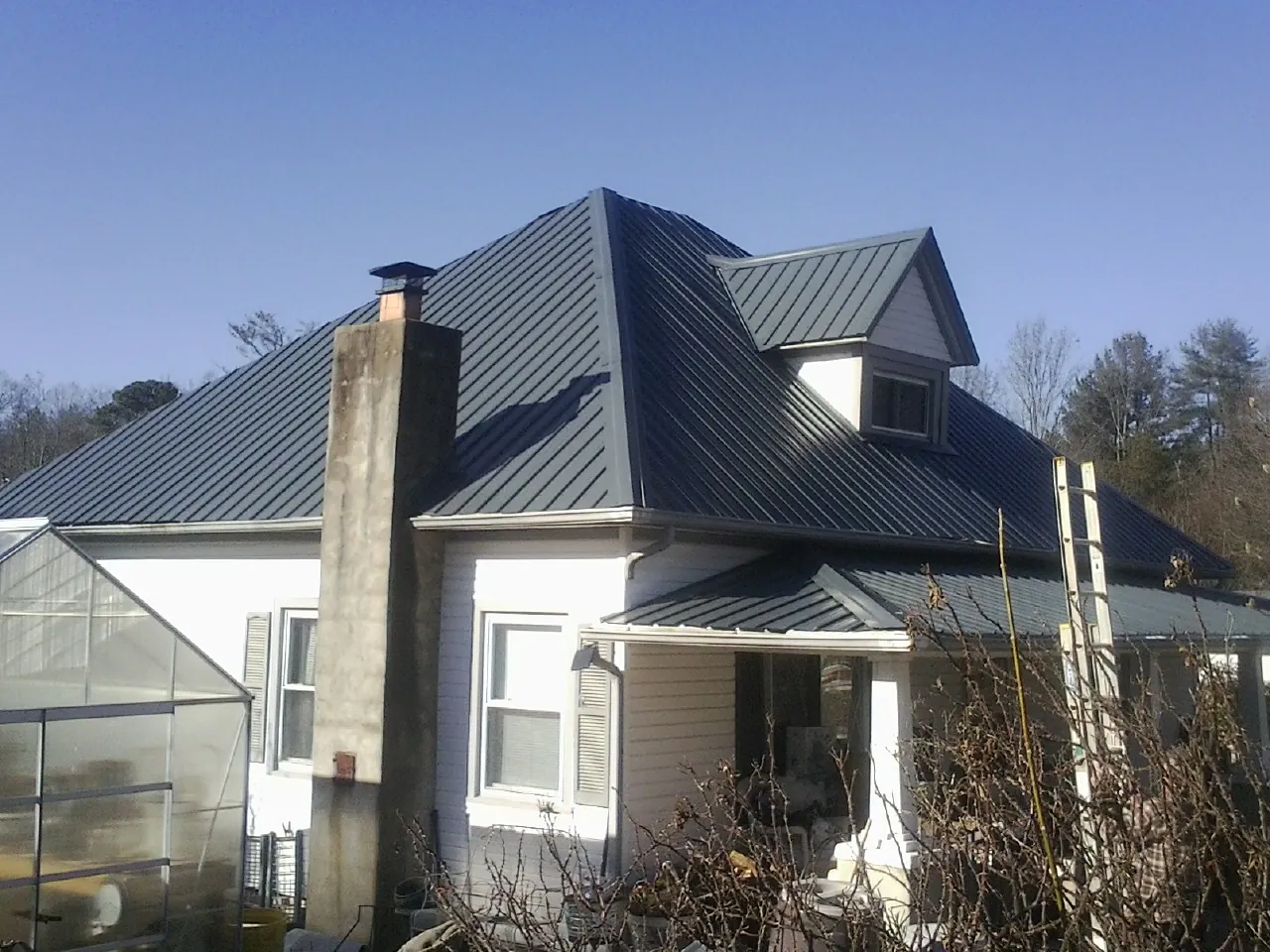 Dark blue standing seam metal roof on a white farmhouse with dormer — Slate & Tile Roof Repair by Roofing Brothers in Atherton
