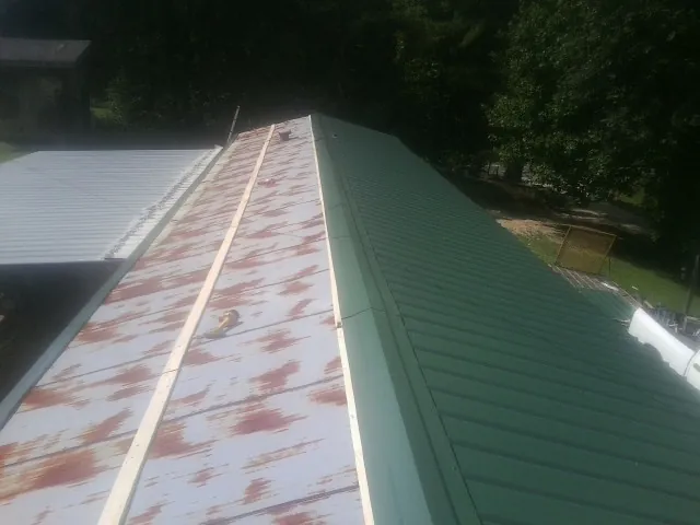 Old rusted panels beside newly installed green metal roofing — Wind Damage Roof Repair by Roofing Brothers in Atherton