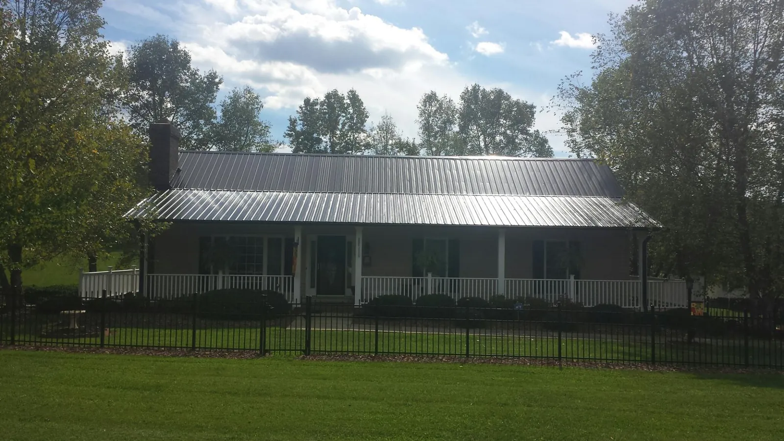 Gray metal roof on a brick ranch with a full width front porch — Gutter Guard Installation work by our crew in Atherton