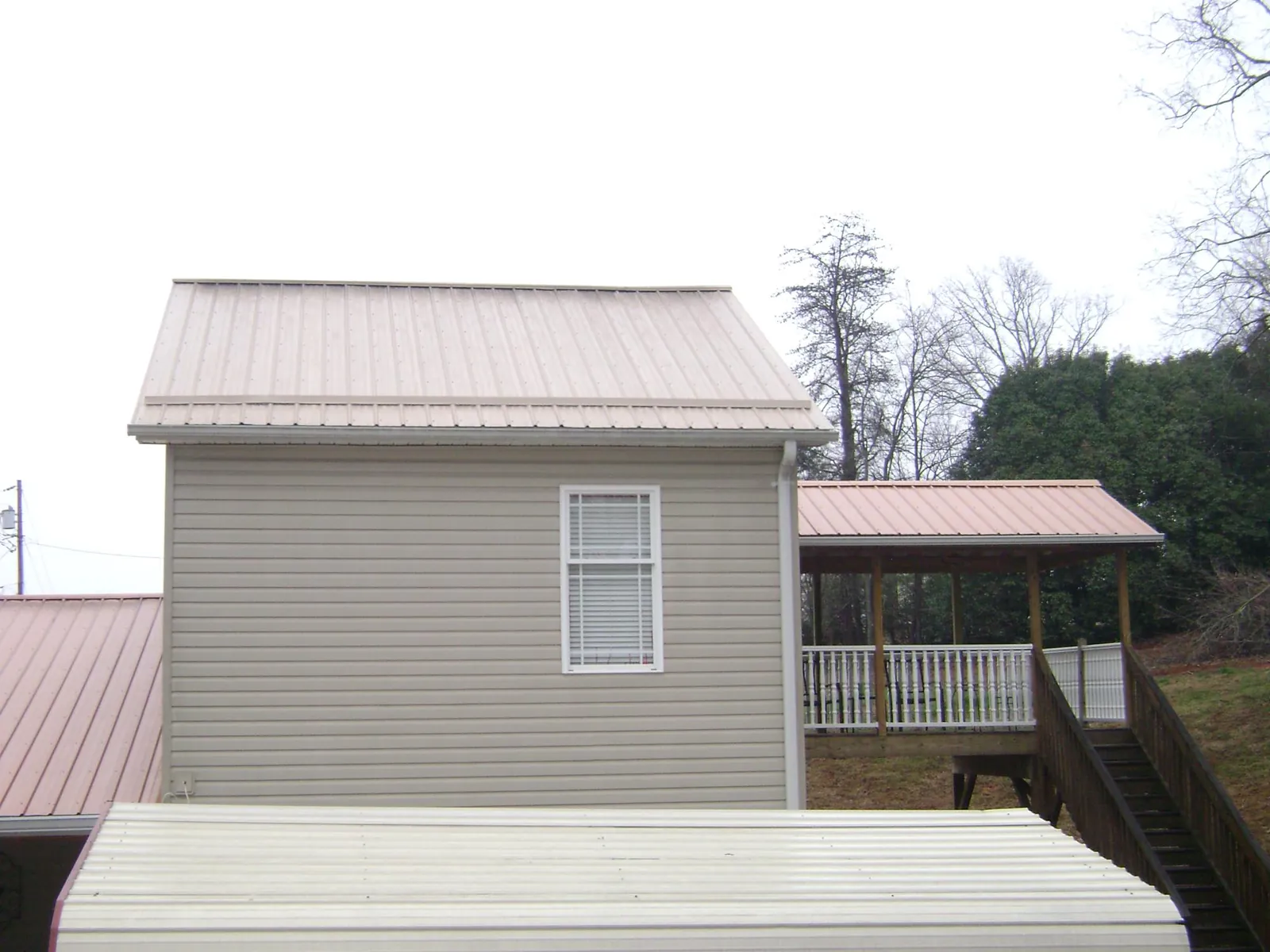Tan metal roofs on a two story addition and attached porch, from a Roof Replacement job in Atherton