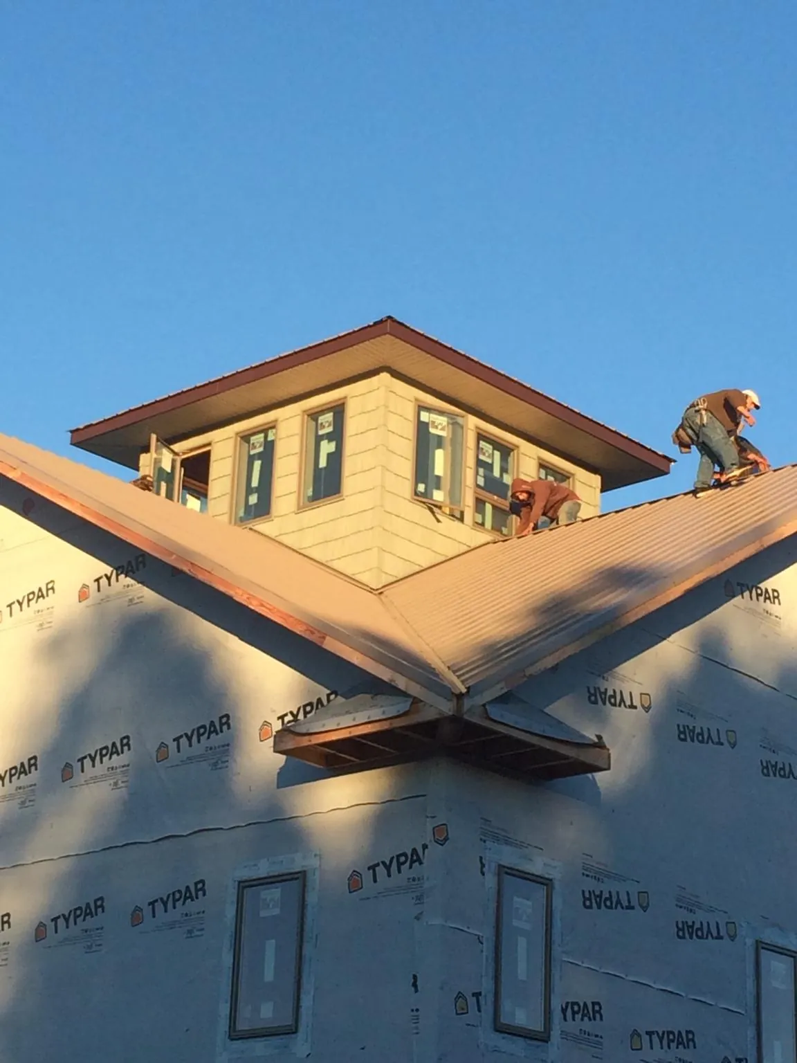 Roofers working around a rooftop cupola on a new metal roof at sunset — Roof Waterproofing in Atherton by Roofing Brothers